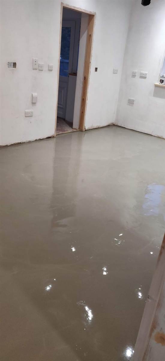 During — self-levelling compound poured across the full floor, mirror-smooth and ready for tiling